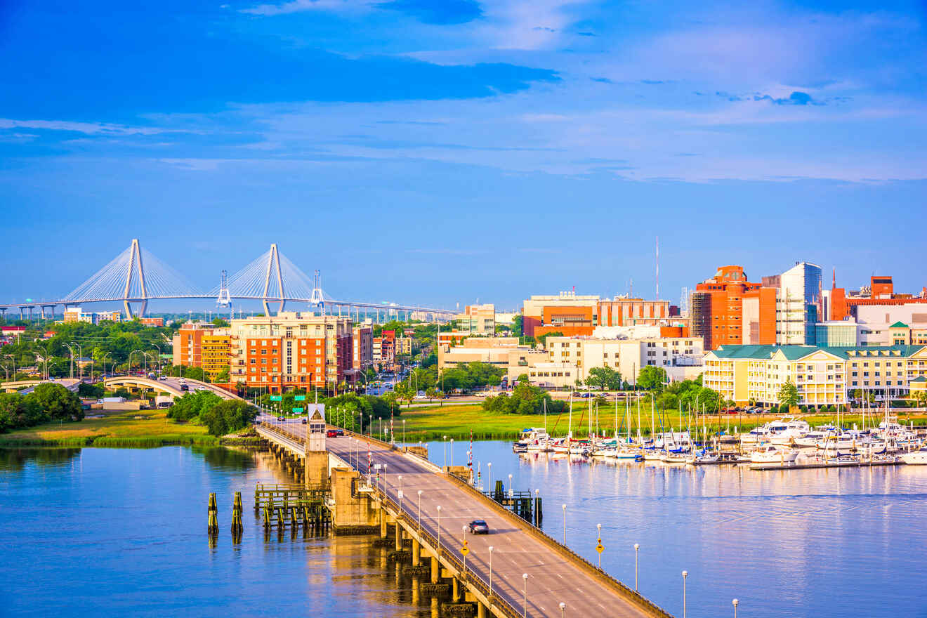 Sunset view of Charleston waterfront with the Ravenel Bridge spanning the Cooper River, downtown skyline, and a marina filled with boats.